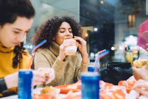 two young women multiethnic indoor eating at fast food - food an